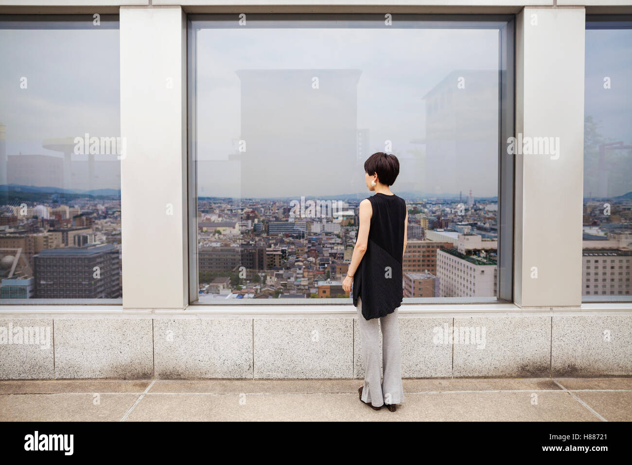 Une femme debout à la recherche sur une ville à partir d'un point d'écoute élevés. Banque D'Images