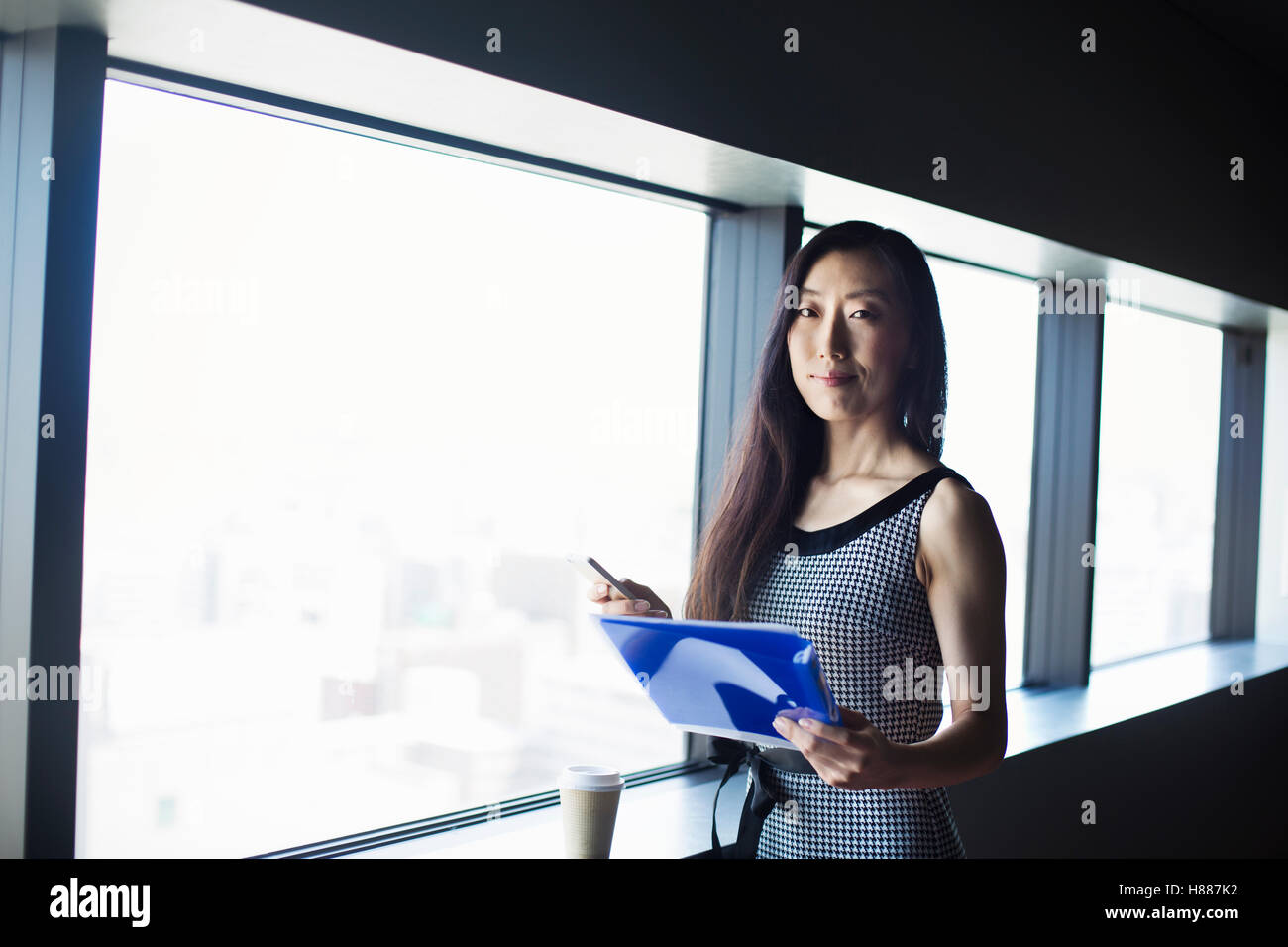 Une femme d'affaires par une fenêtre avec une vue sur la ville, Banque D'Images Une femme d'affaires par une fenêtre avec une vue sur la ville, Banque D'Images