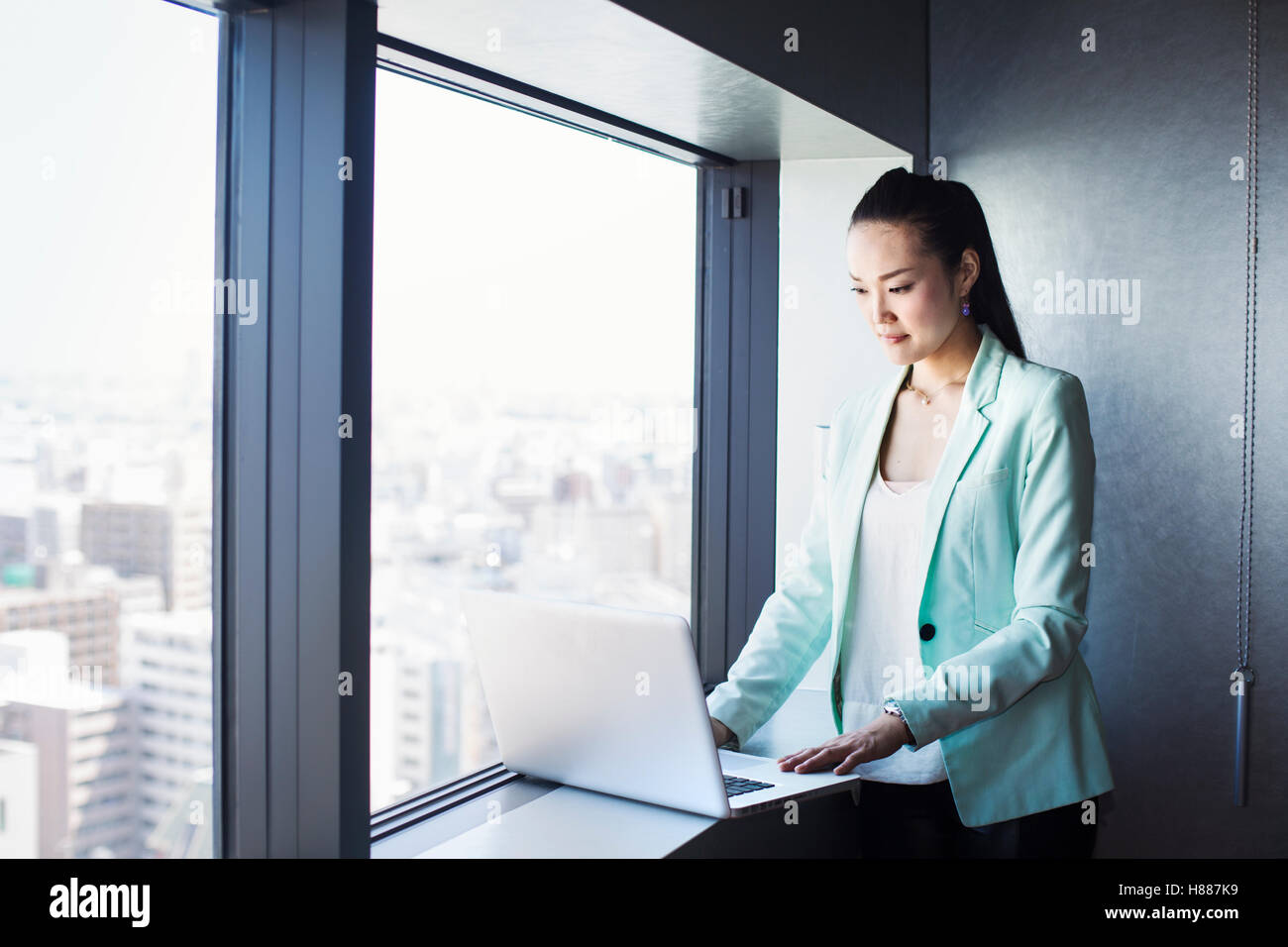 Une femme d'affaires par une fenêtre en utilisant son ordinateur portable. Banque D'Images Une femme d'affaires par une fenêtre en utilisant son ordinateur portable. Banque D'Images