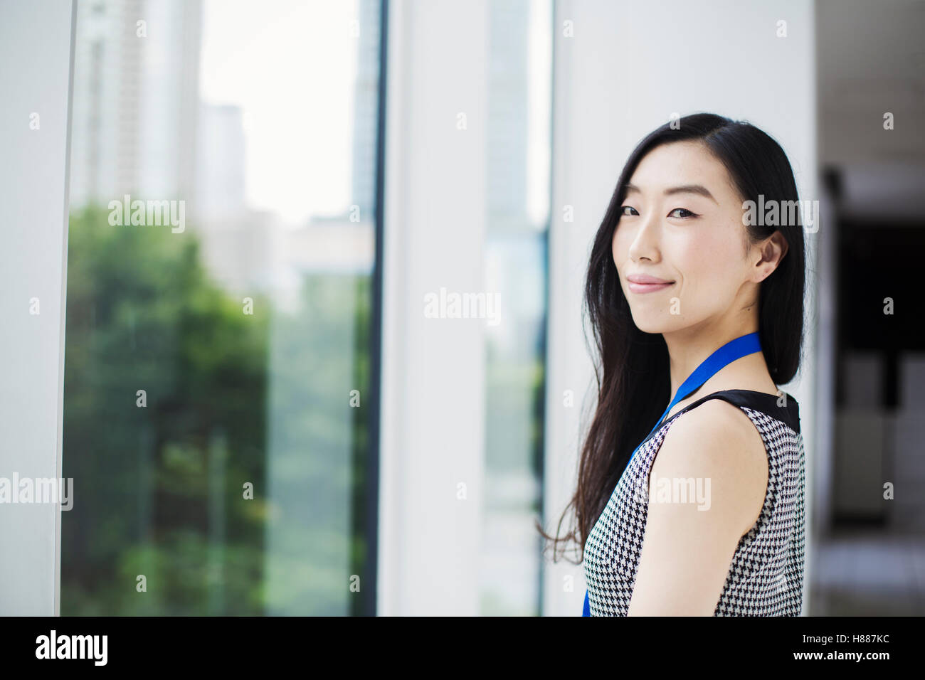 Une femme d'affaires par une fenêtre avec une vue sur la ville, Banque D'Images Une femme d'affaires par une fenêtre avec une vue sur la ville, Banque D'Images