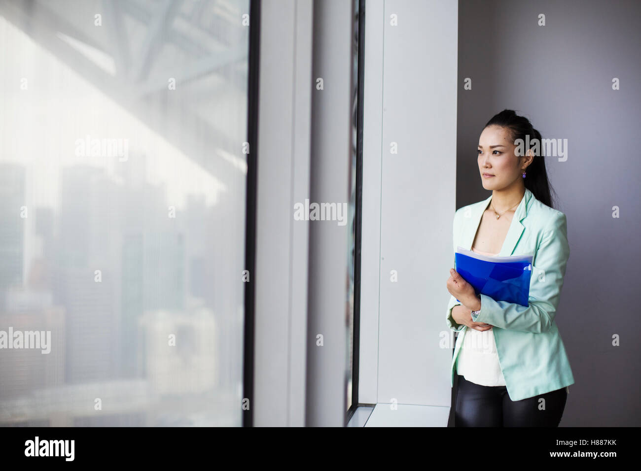 Une femme d'affaires par une fenêtre avec une vue sur la ville, Banque D'Images Une femme d'affaires par une fenêtre avec une vue sur la ville, Banque D'Images