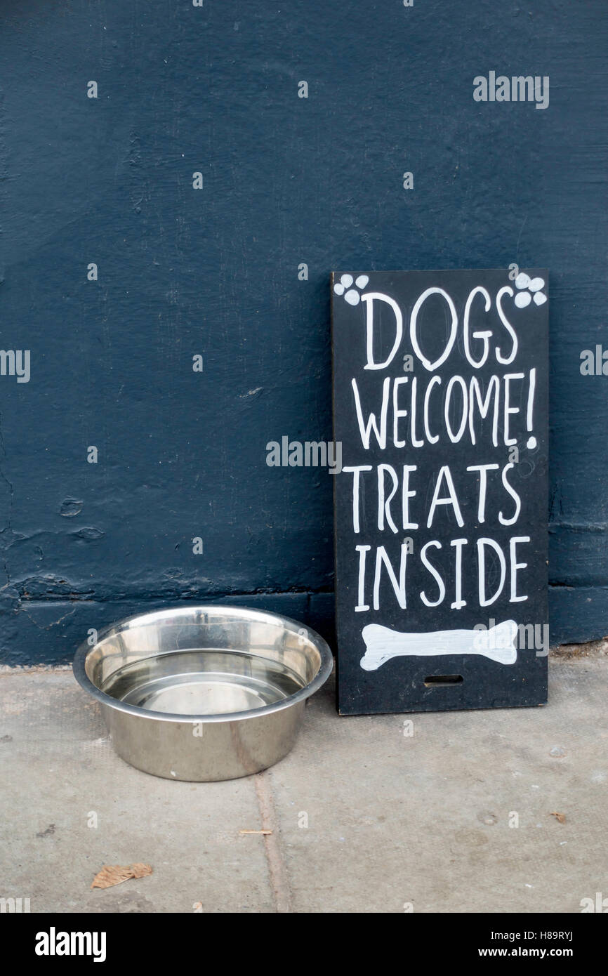 En dehors d'un Pet Shop la cuvette d'eau et un signe - Chiens bienvenus traite à l'intérieur Banque D'Images
