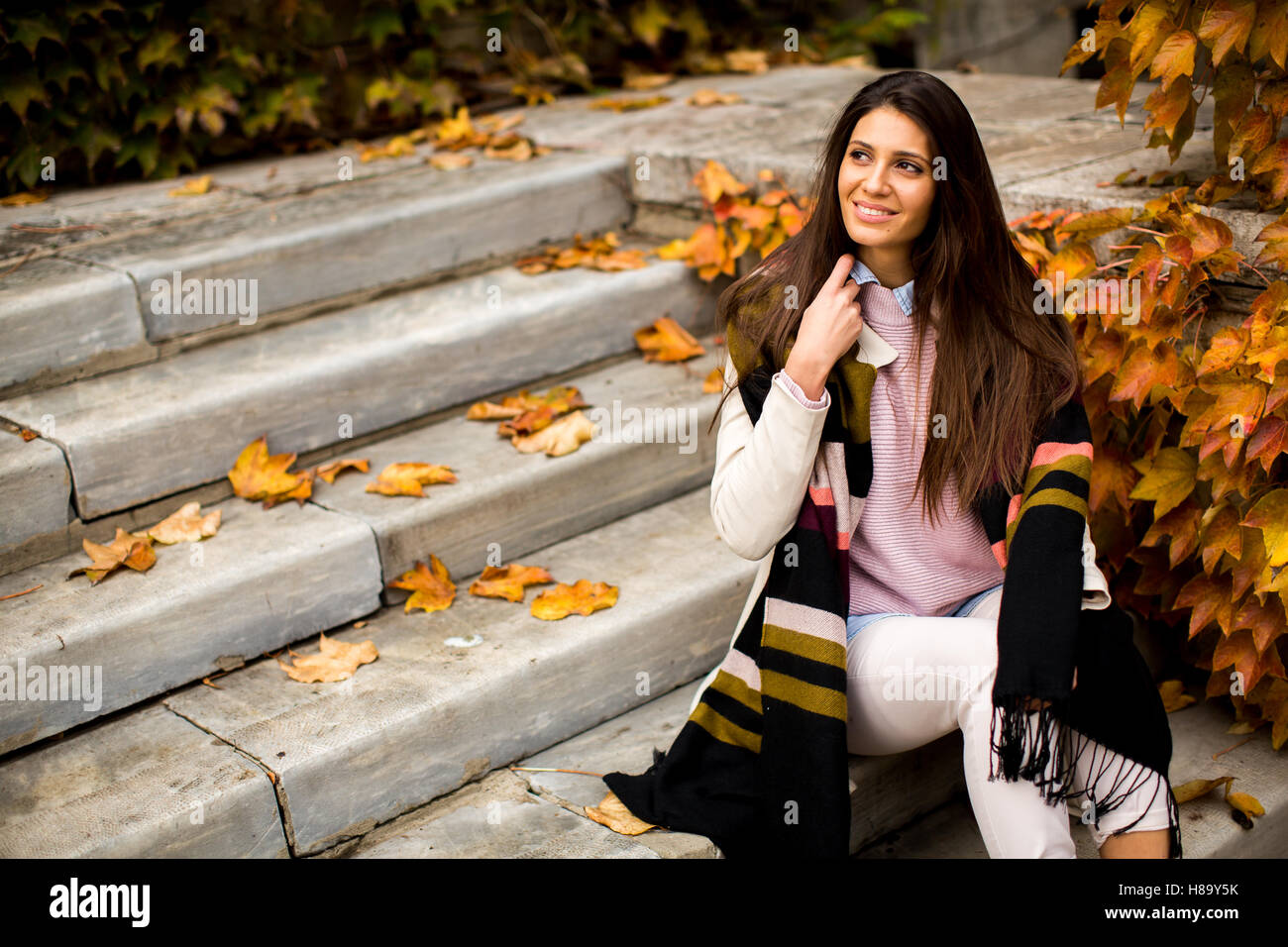 Jeune femme assise sur les marches à l'extérieur à l'automne 24 Banque D'Images