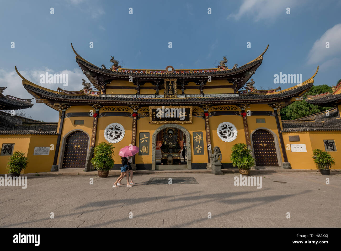 Deux filles w/ pink parasol de marche avant d'un jaune vif sur l'île de Temple Jiangxin Jiangxin en rivière Oujiang à Shanghai, Chine. Banque D'Images