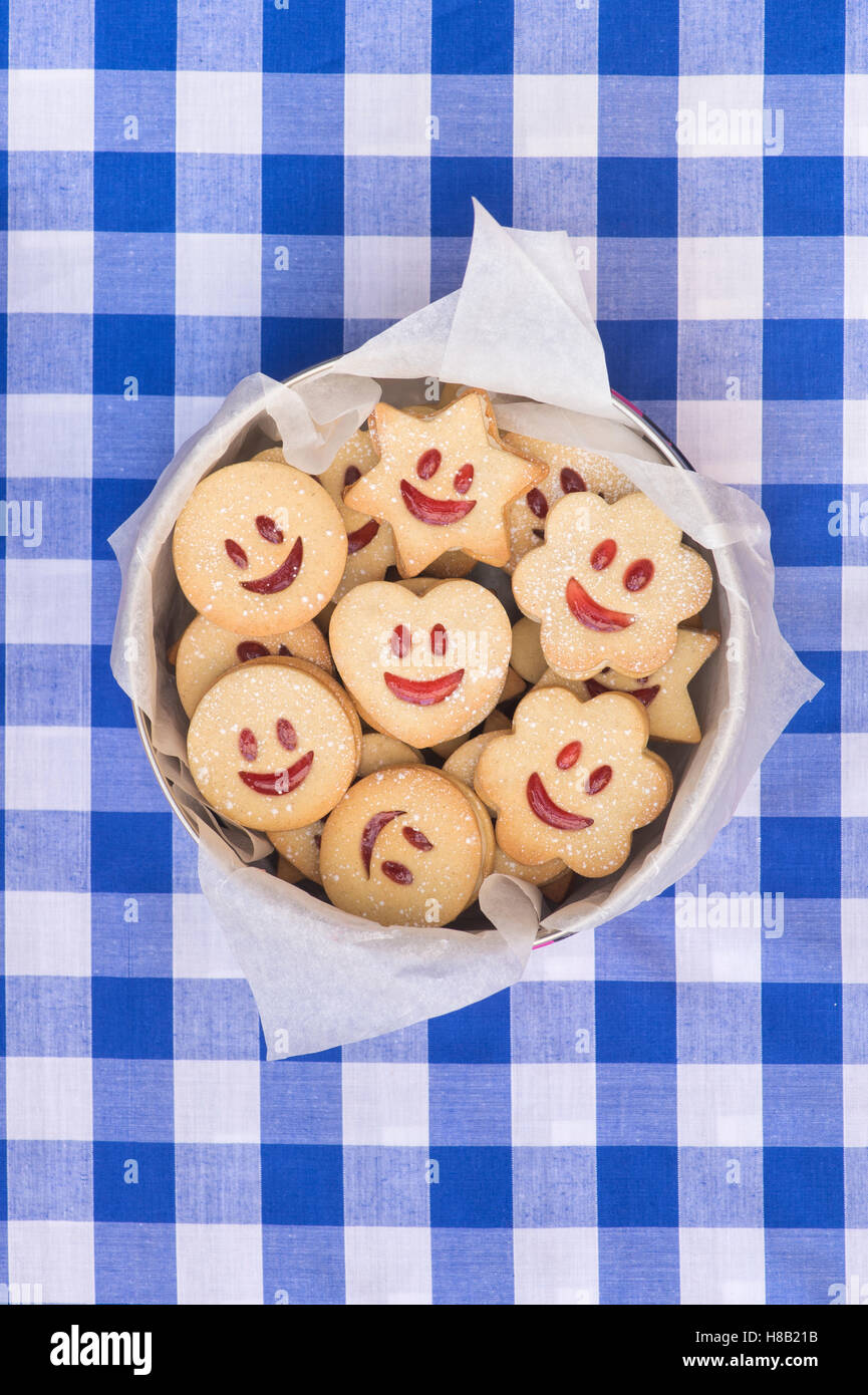 Jammie Dodgers fait maison. Visage souriant des biscuits dans une boîte en fer Banque D'Images