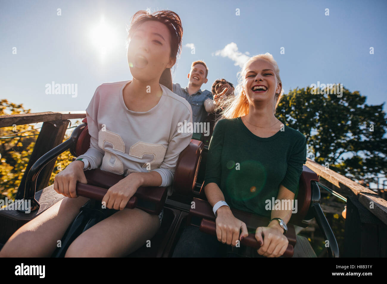 Jeunes amis enthousiastes sur roller coaster ride. Les jeunes s'amuser au parc d'amusement. Banque D'Images