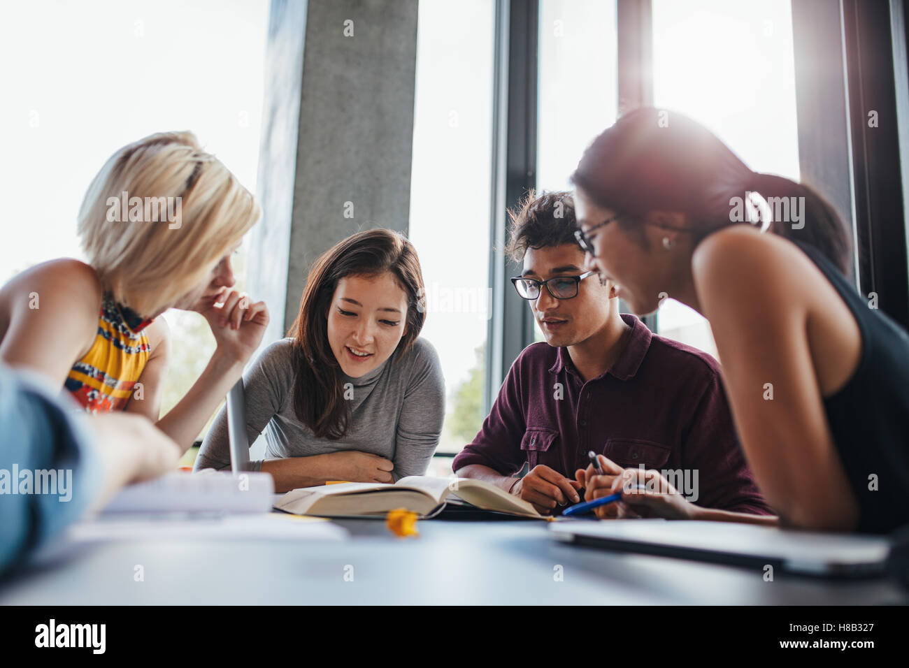 étudiants universitaires en coopération avec leur affectation à la bibliothèque. Groupe de jeunes assis à table lisant des livres. Banque D'Images