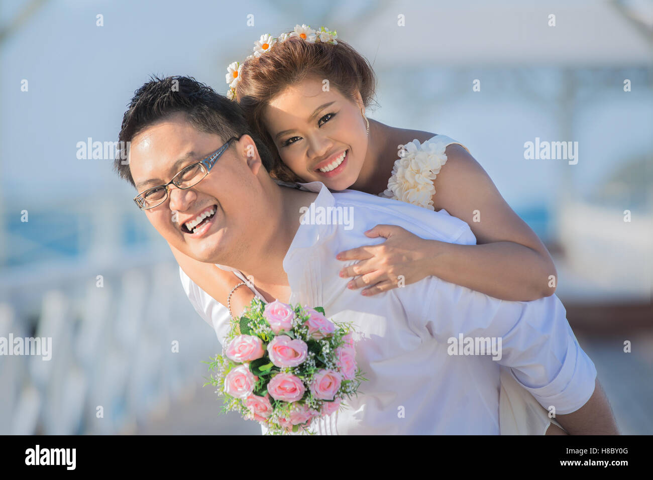 Portrait of happy wedding couple hugging et regardant la caméra. Couple de mariage asiatique près de la mer. Banque D'Images