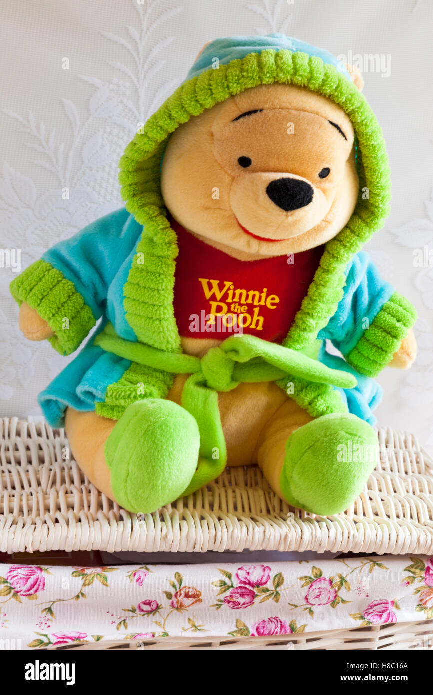 Winnie l'Ourson doux jouet cudly portant robe de chambre avec capuche et pantoufles assis sur un panier en osier Banque D'Images