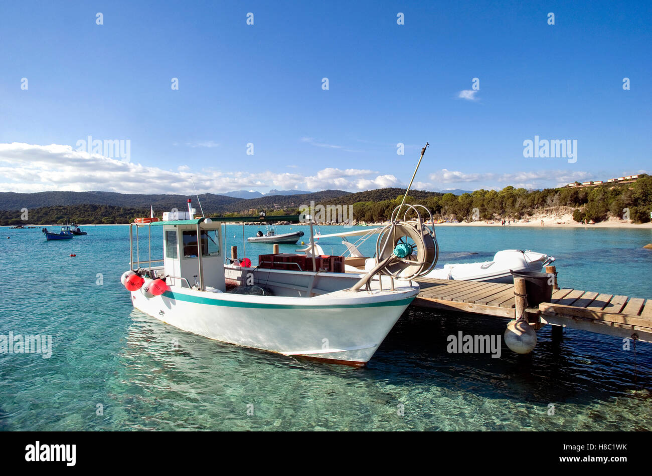 Porto Vecchio (Corse du Sud) : plage de santa giulia et bateau de pêche dans l'avant-plan. Banque D'Images