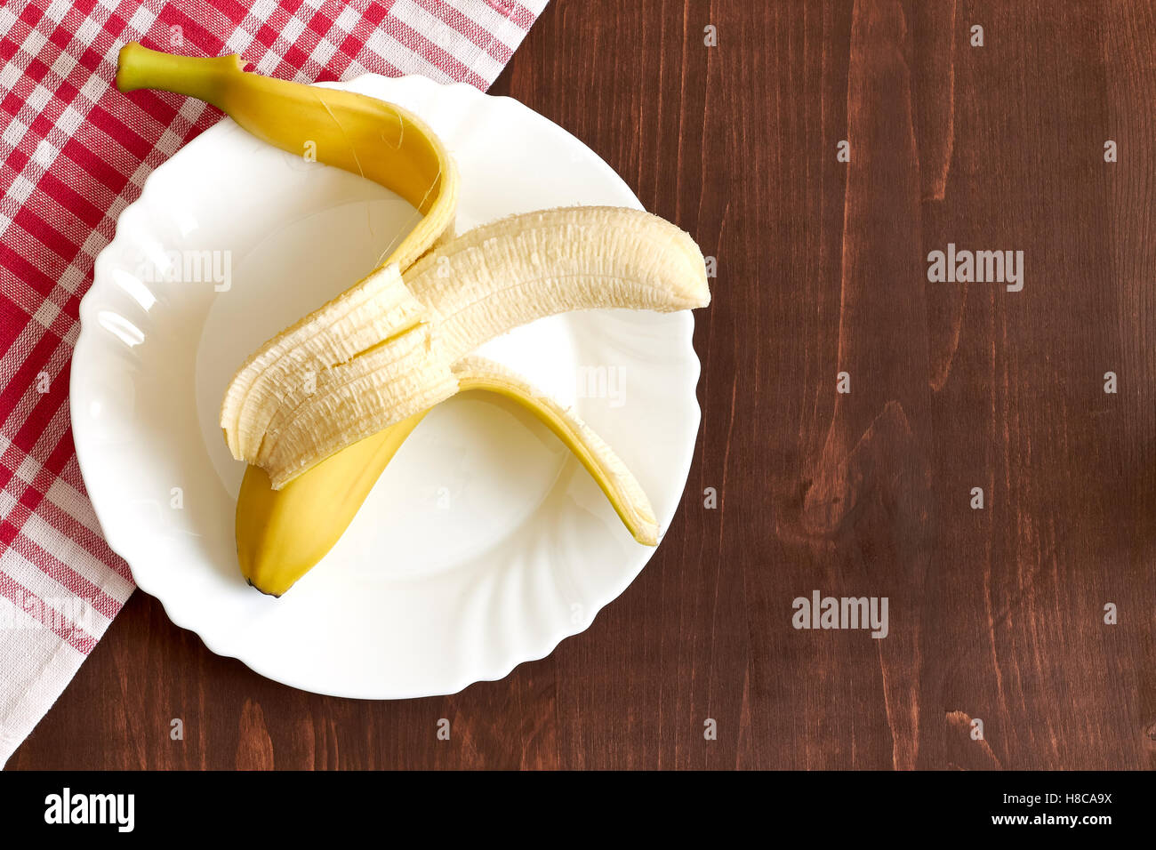 Une banane pelée sur plaque blanche. Concept de droit dans le cadre de la diététique. Vue de dessus avec beaucoup d'espace de copie Banque D'Images