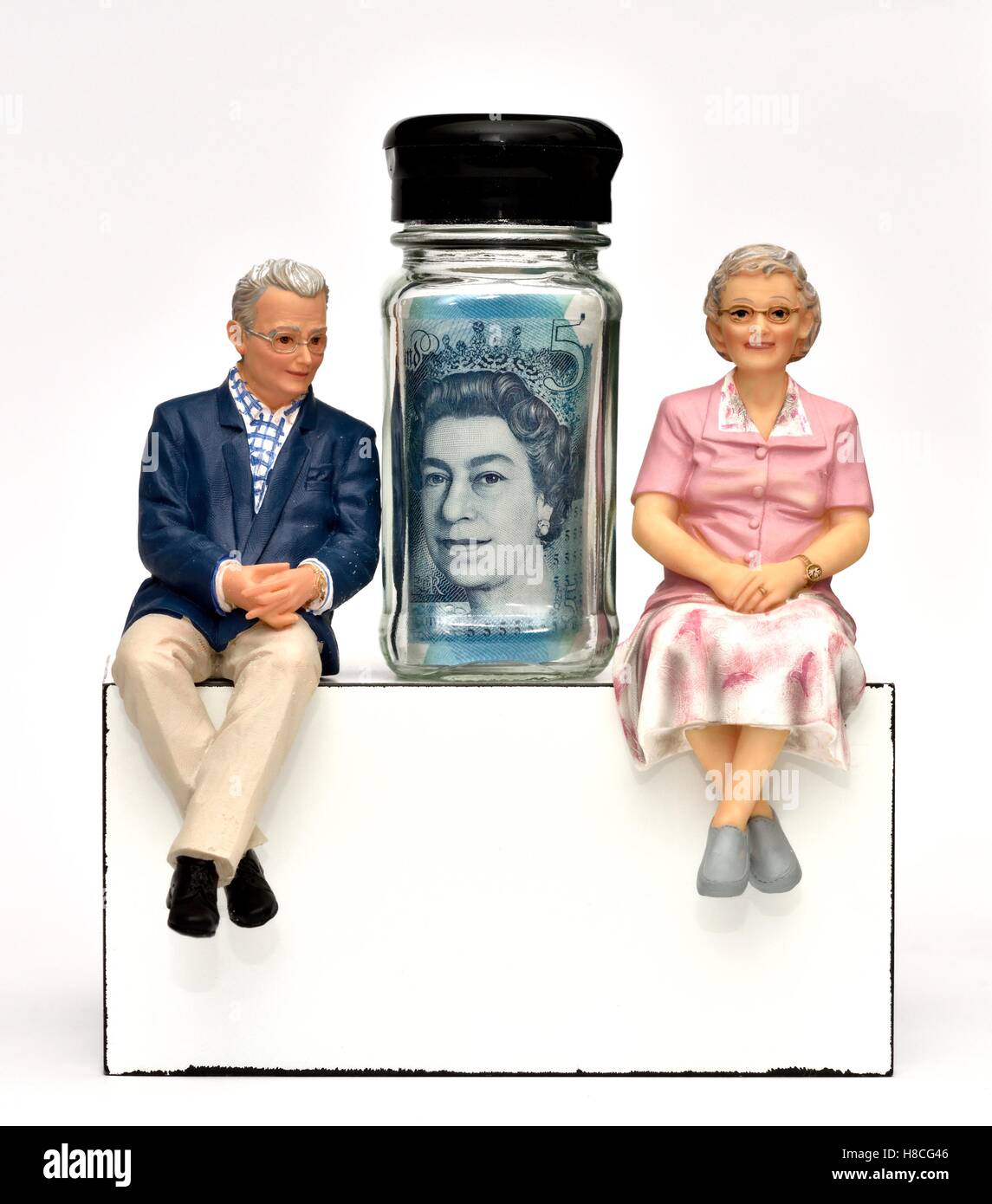 Un pensionné, figurine couple avec le Queens Head sur une note cinq livres dans un petit pot en verre Banque D'Images