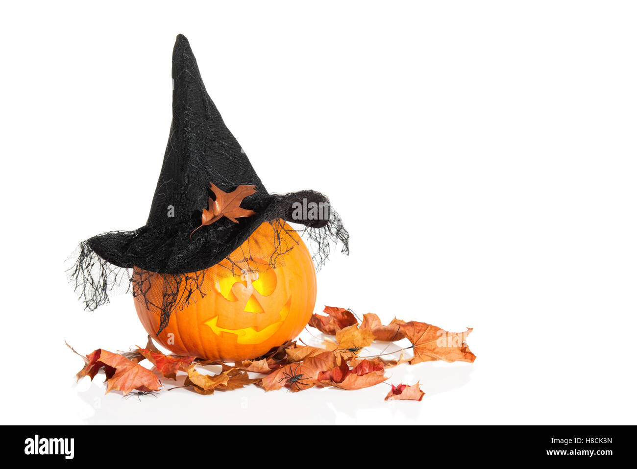 Jack O Lantern assis sur les feuilles d'automne portant un chapeau de sorcière Banque D'Images
