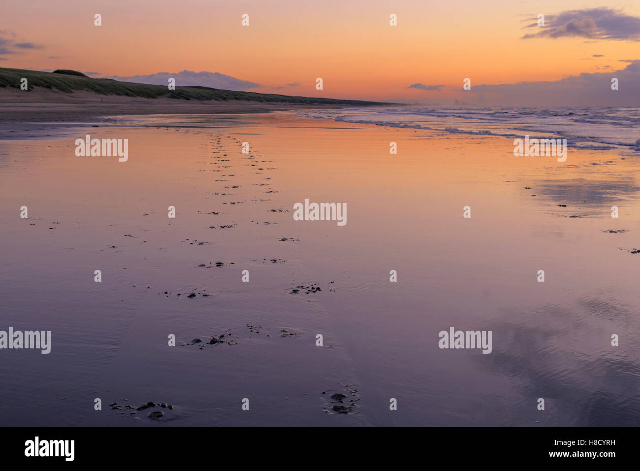 Coucher de soleil pastel réflexions avec des traces de pas dans le sable sur la plage de Katwijk aan Zee, Hollande méridionale, Pays-Bas. Banque D'Images