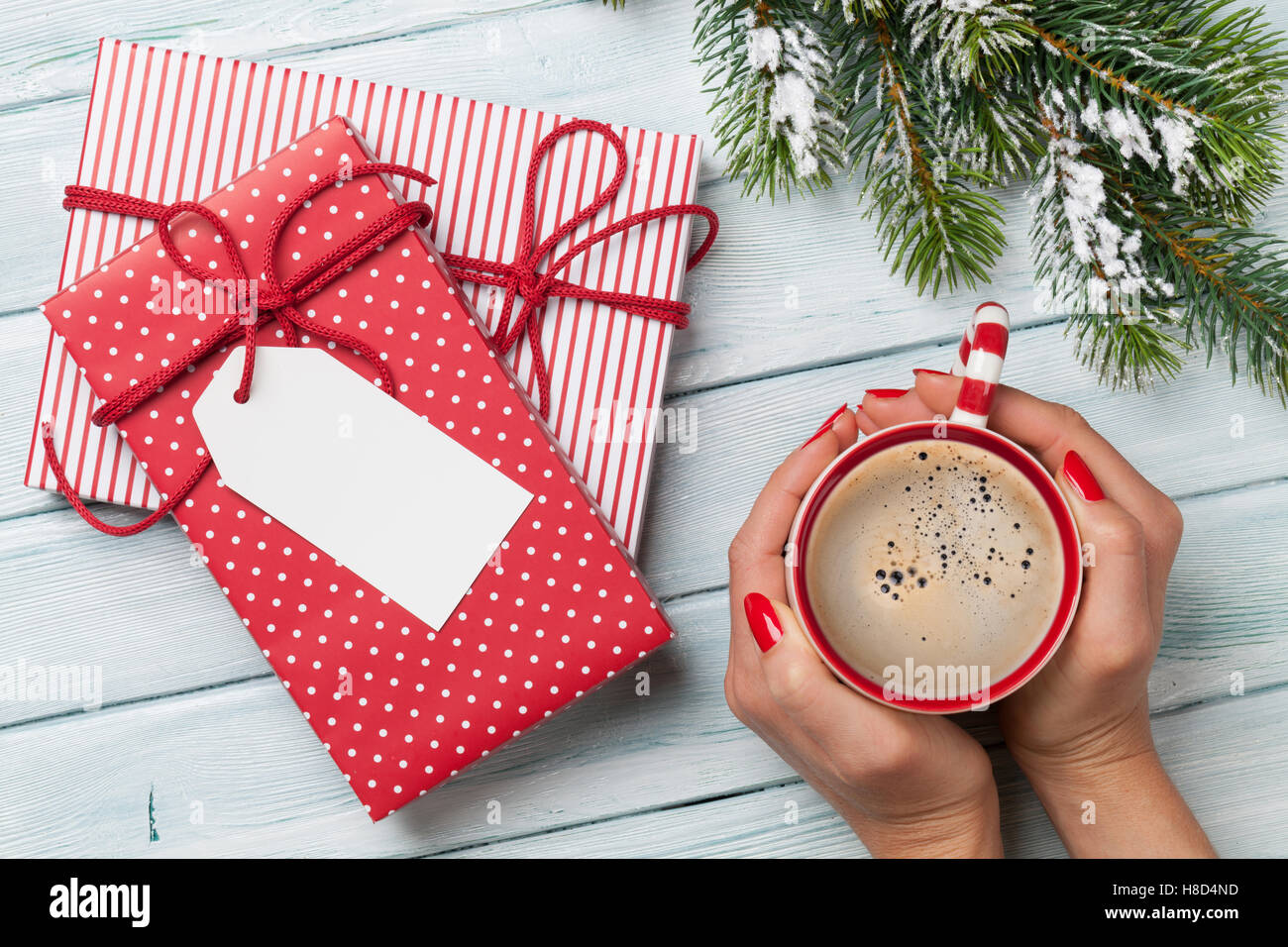 Female hands holding Coffee cup, cadeaux de Noël et de neige sapin au-dessus de table en bois. Top View with copy space Banque D'Images