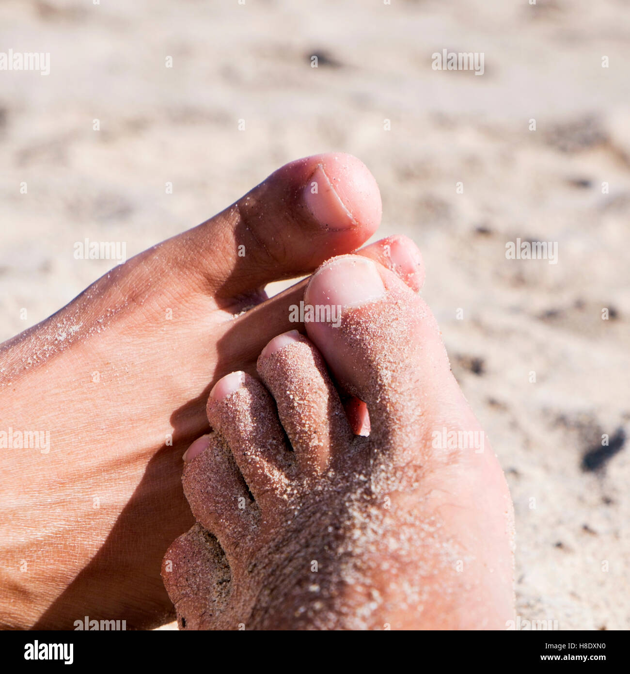 Gros plan des pieds de deux jeunes hommes jouer footsie sur la plage Banque D'Images