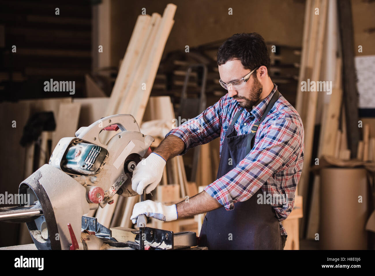 À l'aide d'un entrepreneur d'encadrement tronçonneuse circulaire pour ajuster la longueur des poteaux en bois. Banque D'Images