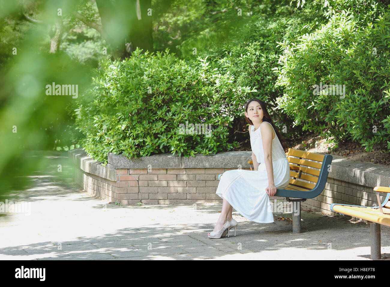 Jeune japonaise assis sur un banc dans un parc de la ville Banque D'Images