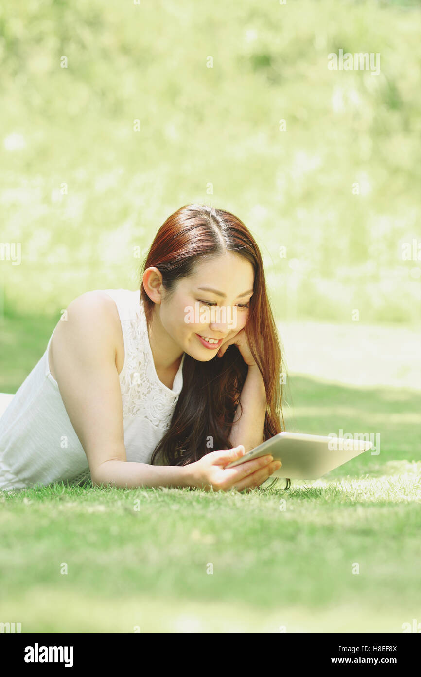 Portrait de jeune japonaise portant sur l'herbe avec tablet Banque D'Images