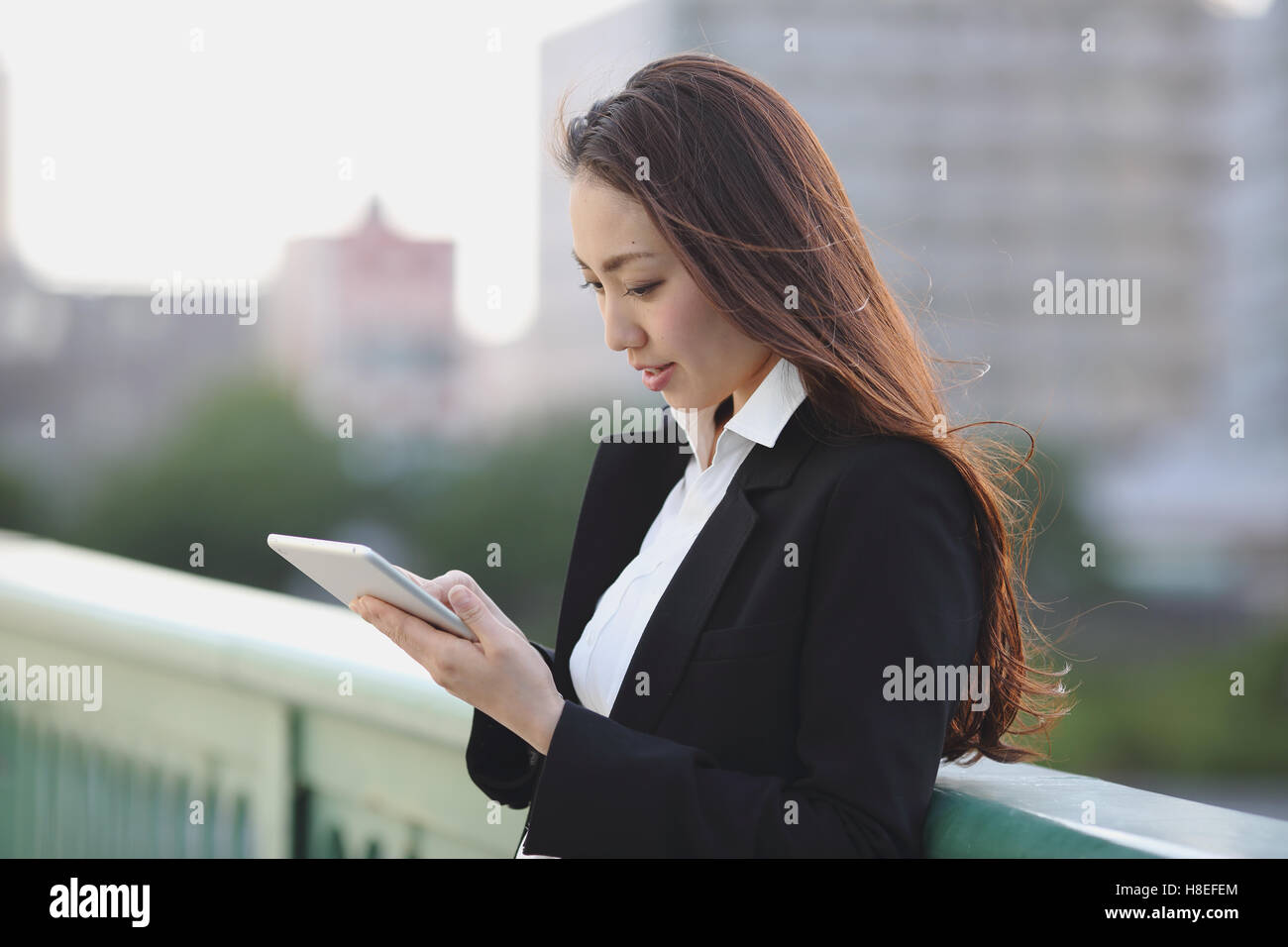 Young Japanese businesswoman with tablet par une rivière centre de Tokyo Banque D'Images