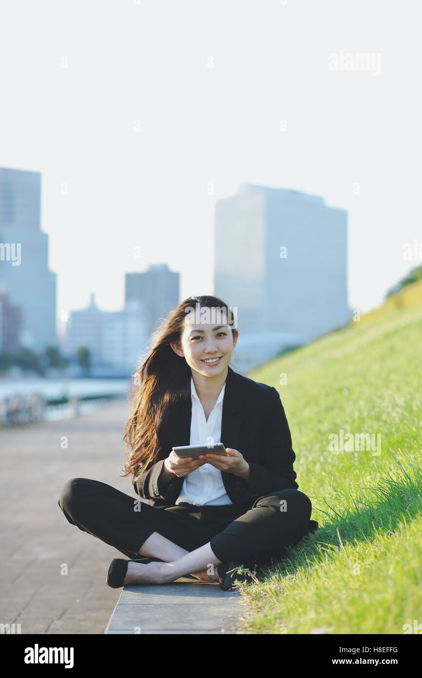 Young Japanese businesswoman with tablet par une rivière centre de Tokyo Banque D'Images