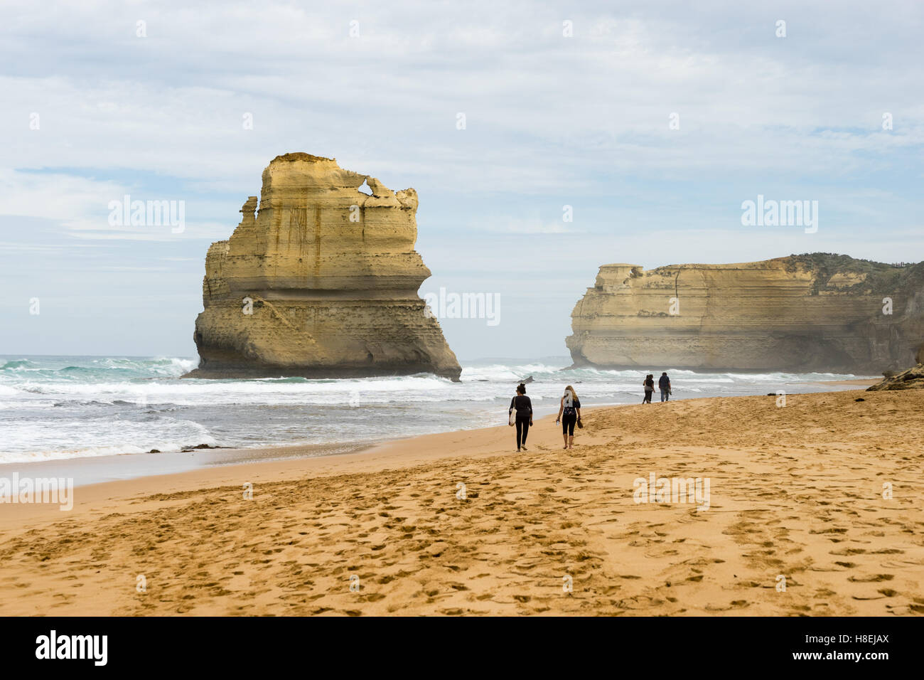 Les gens marchent le long d'une plage avec l'un des Douze Apôtres formation géologique dans l'arrière-plan, Victoria, Australie, Pacifique Banque D'Images