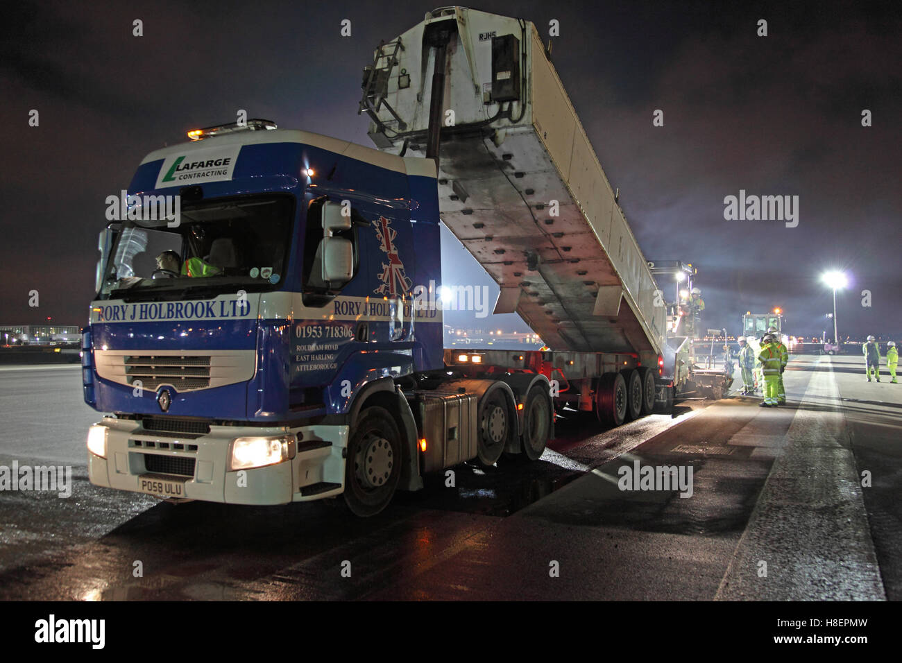 Un camion décharge l'asphalte dans une machine de surfaçage de la route pendant le refaçage de nuit de la piste sud de l'aéroport d'Heathrow. Londres, Royaume-Uni Banque D'Images