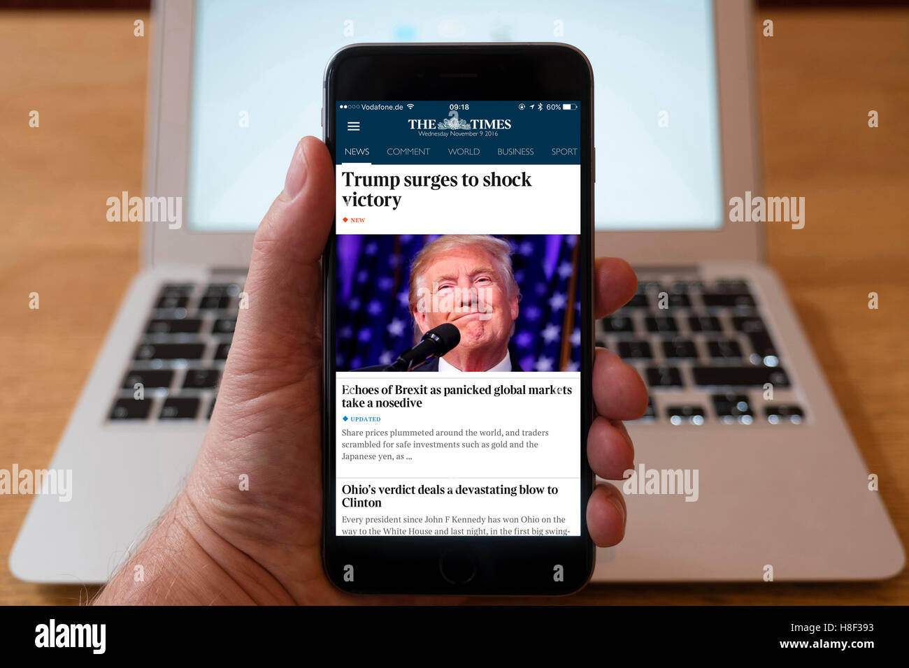 Détail de l'iPhone téléphone mobile intelligent en ligne montrant des journaux page titre de The Times après l'atout de Donald's victo Banque D'Images