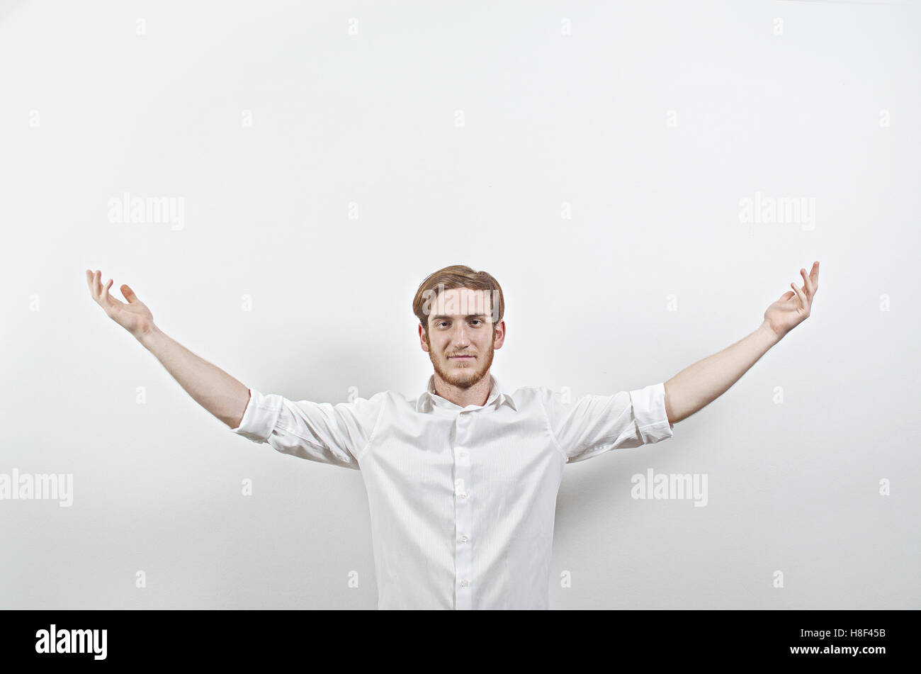 Les jeunes adultes de sexe masculin en chemise blanche Gesturing, bras levés, Wide Open Banque D'Images