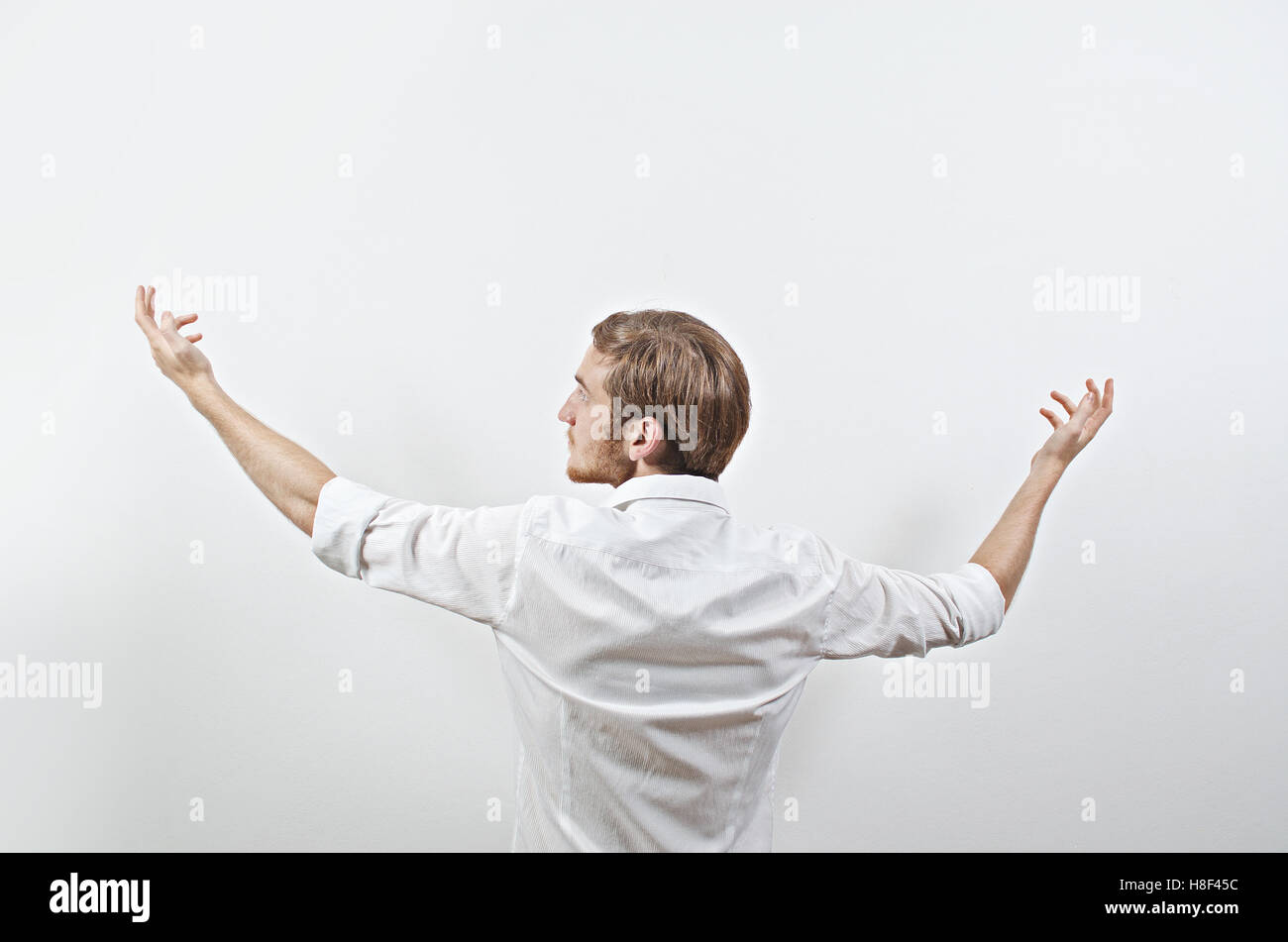 Les jeunes adultes de sexe masculin en chemise blanche gesticulant bras levés, Wide Open Banque D'Images