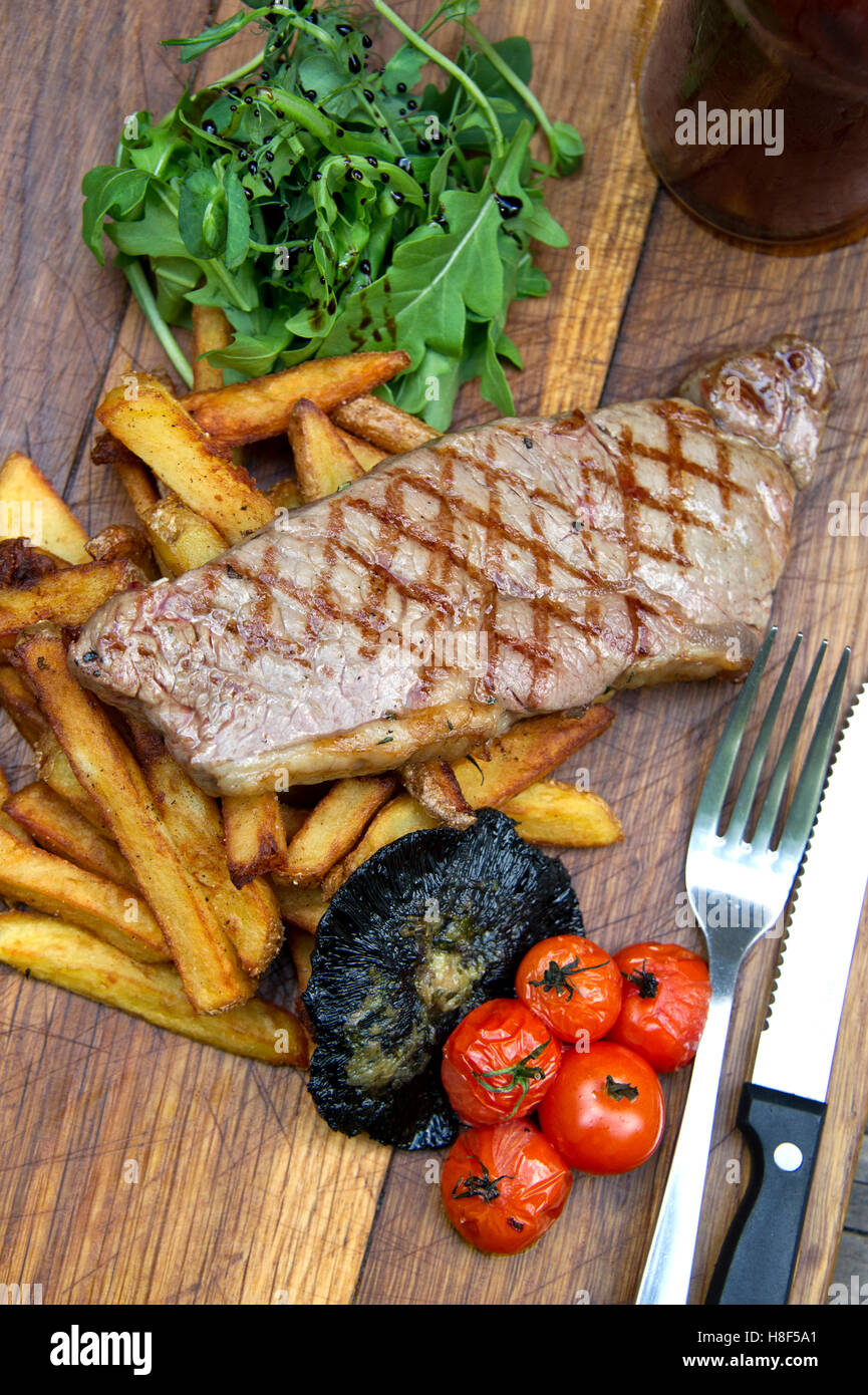 Steak et frites avec les champignons et les tomates servi sur un plateau en bois. une cuisine britannique de sécurité alimentaire Banque D'Images