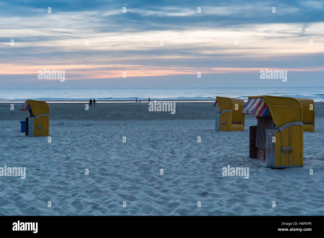 En osier et en bois jaune chaises de plage reposer de côté dans la lumière du soir sur la plage déserte presque à Egmond aan Zee Banque D'Images