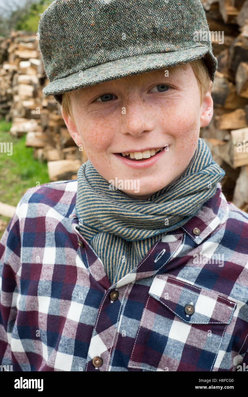 Garçon en chemise à carreaux, un foulard, et hat holding une hache en face  d'un tas de bois de chauffage dans une ferme Photo Stock - Alamy