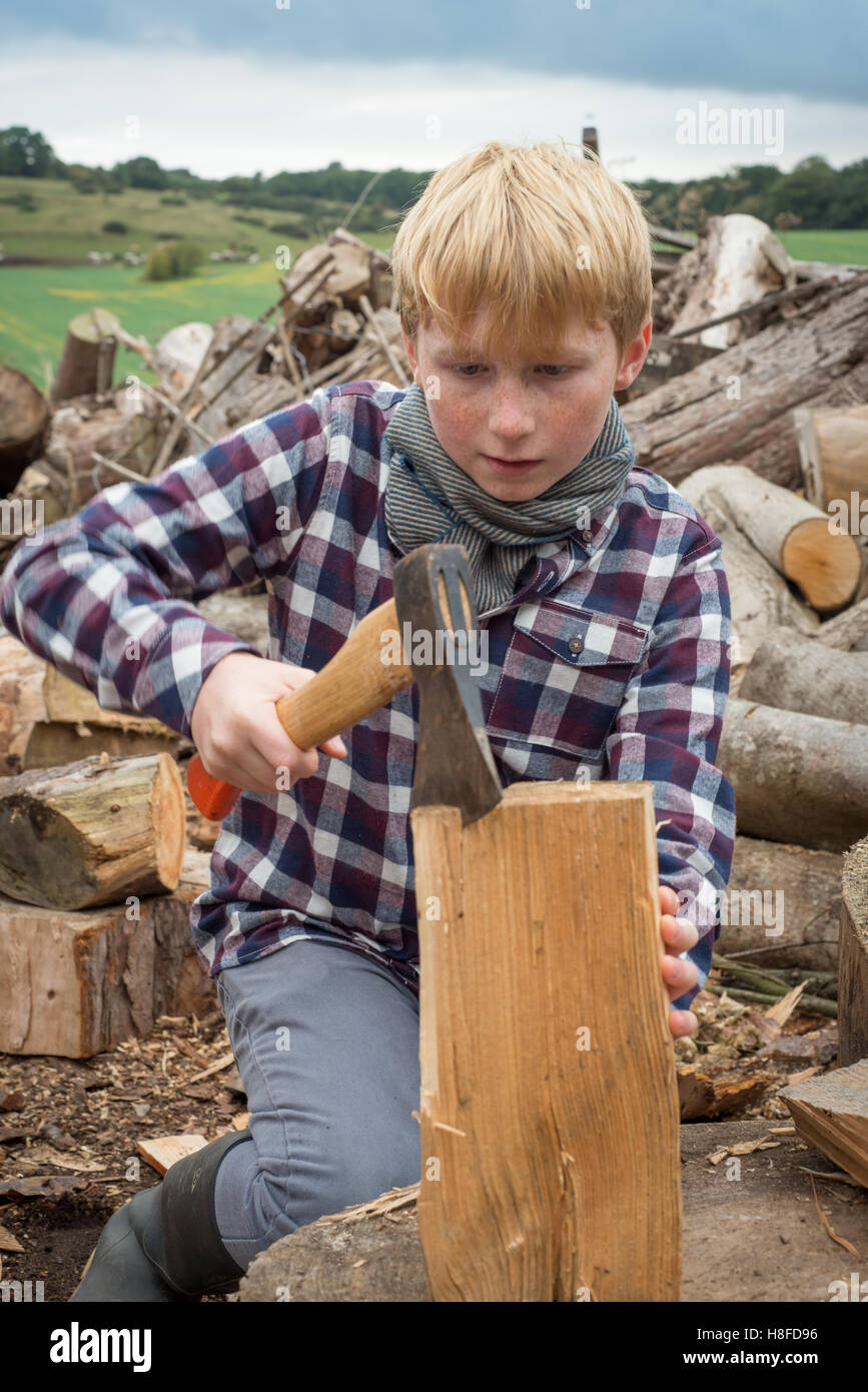 Jeune garçon bûcheron couper un morceau de bois avec une hache Banque D'Images