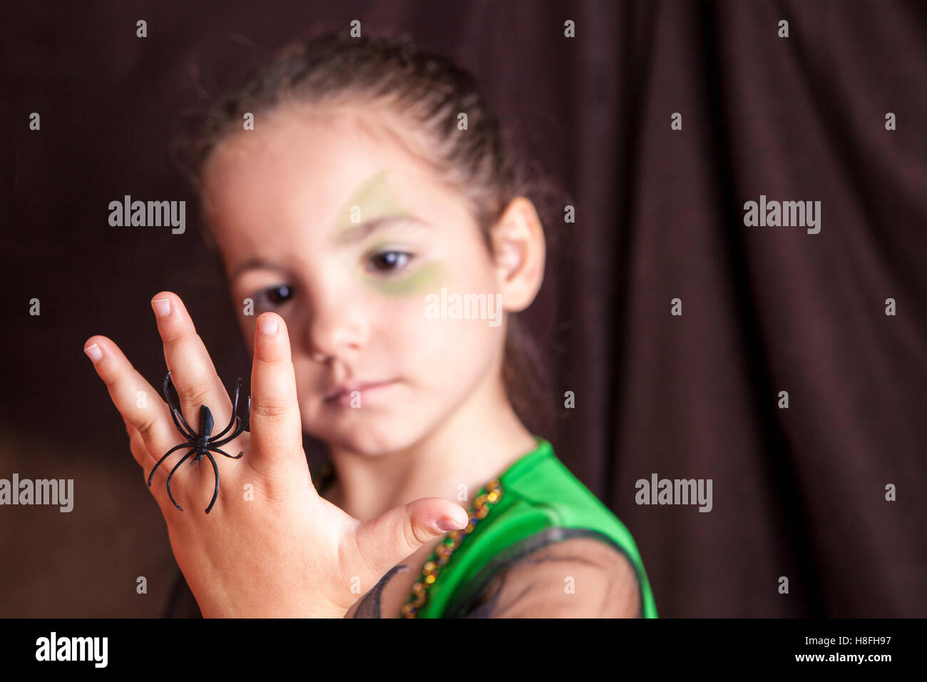 Petite fille mignonne montrant un processus de maquillage pendant l'araignée avant Halloween party Banque D'Images