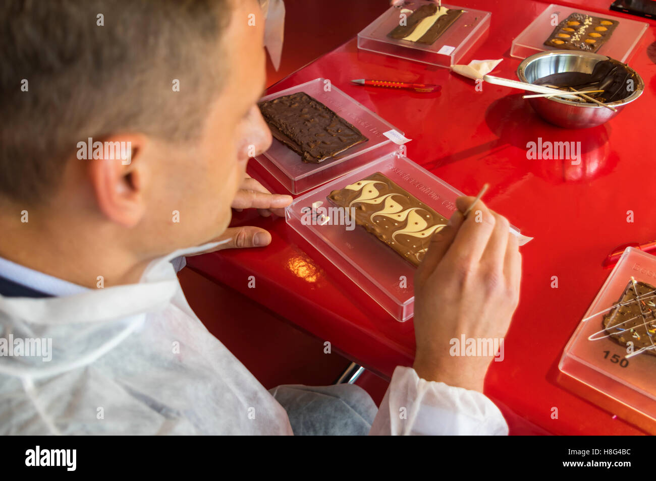 Jeune homme de race blanche visiteur faire sa propre barre de chocolat à l'usine de chocolat Chocolat Frey et musée en Suisse. Banque D'Images