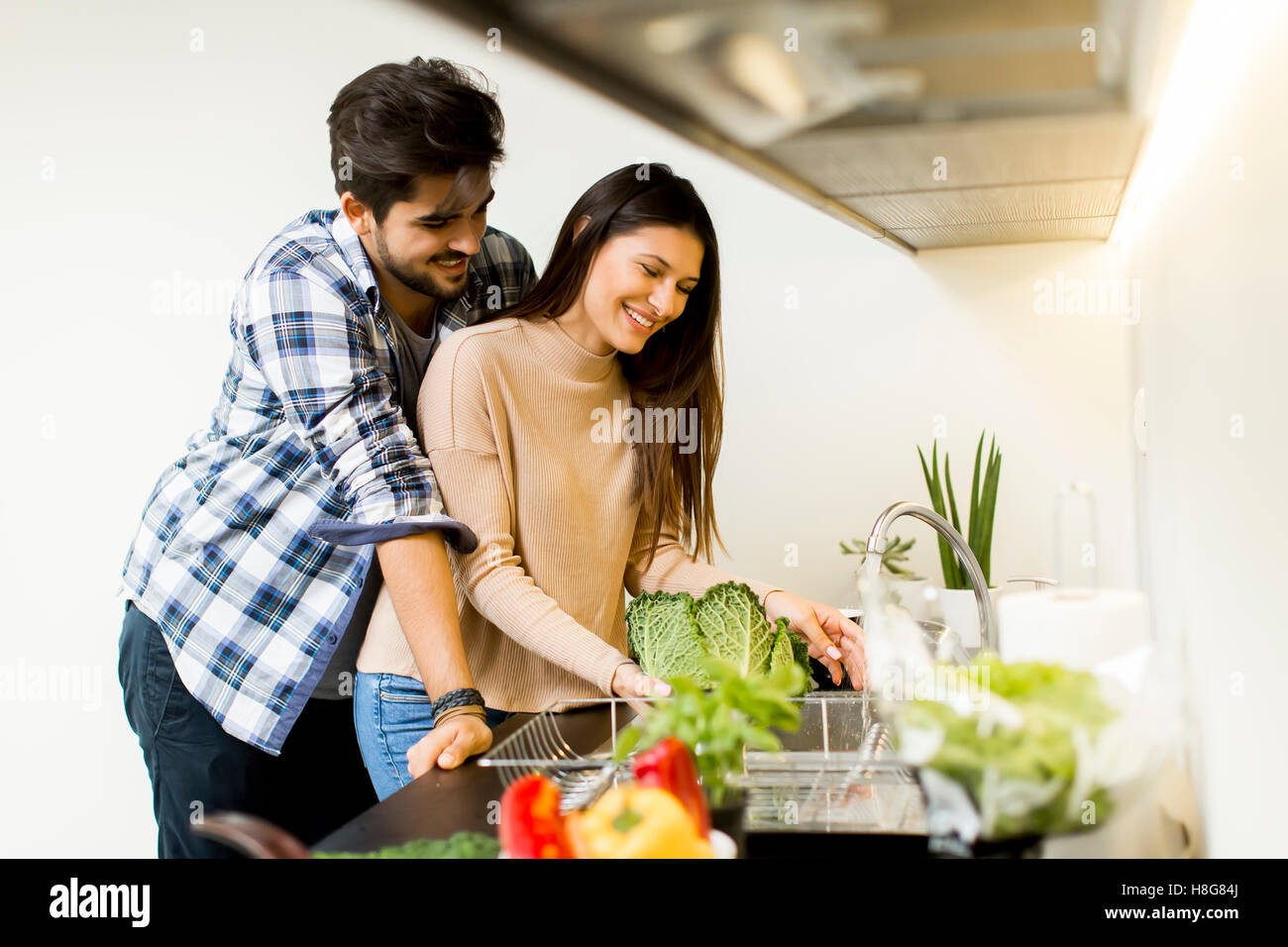 Happy young couple préparer la nourriture dans la cuisine Banque D'Images