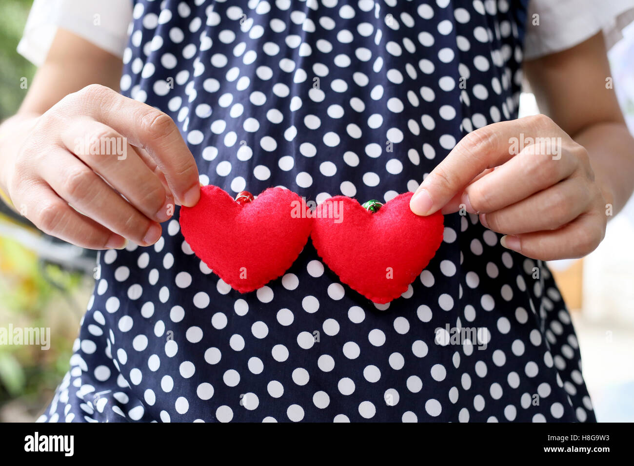 Les femmes enceintes porter des vêtements de maternité bleu marine et un cœur rouge signes figurant sur le ventre. Banque D'Images