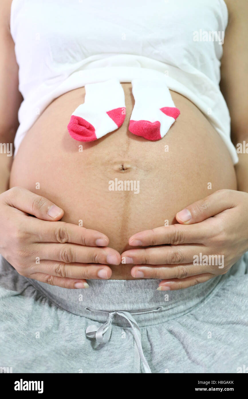 Les femmes enceintes garder sock mis sur ventre concept d'amour pour le bébé. Banque D'Images