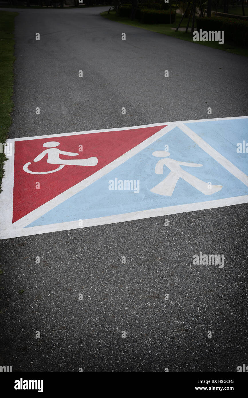 La route d'asphalte dans le parc et avons symbole de personnes handicapées et promenade pour afficher le trajet à l'avant. Banque D'Images