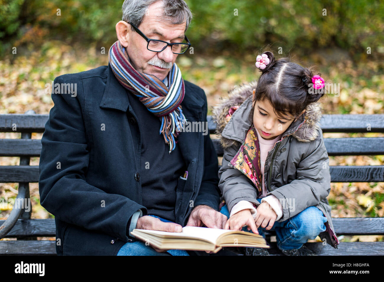 Grand-père et petite-fille de lire un livre à l'automne park Banque D'Images
