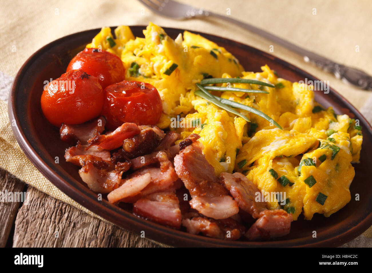 De délicieux œufs brouillés et bacon ciboulette, gros plan sur une plaque horizontale. Banque D'Images