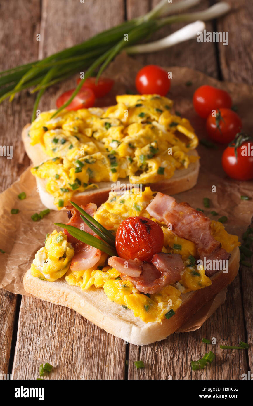 Sandwich fait maison avec des œufs brouillés, bacon et les tomates sur la table. La verticale Banque D'Images
