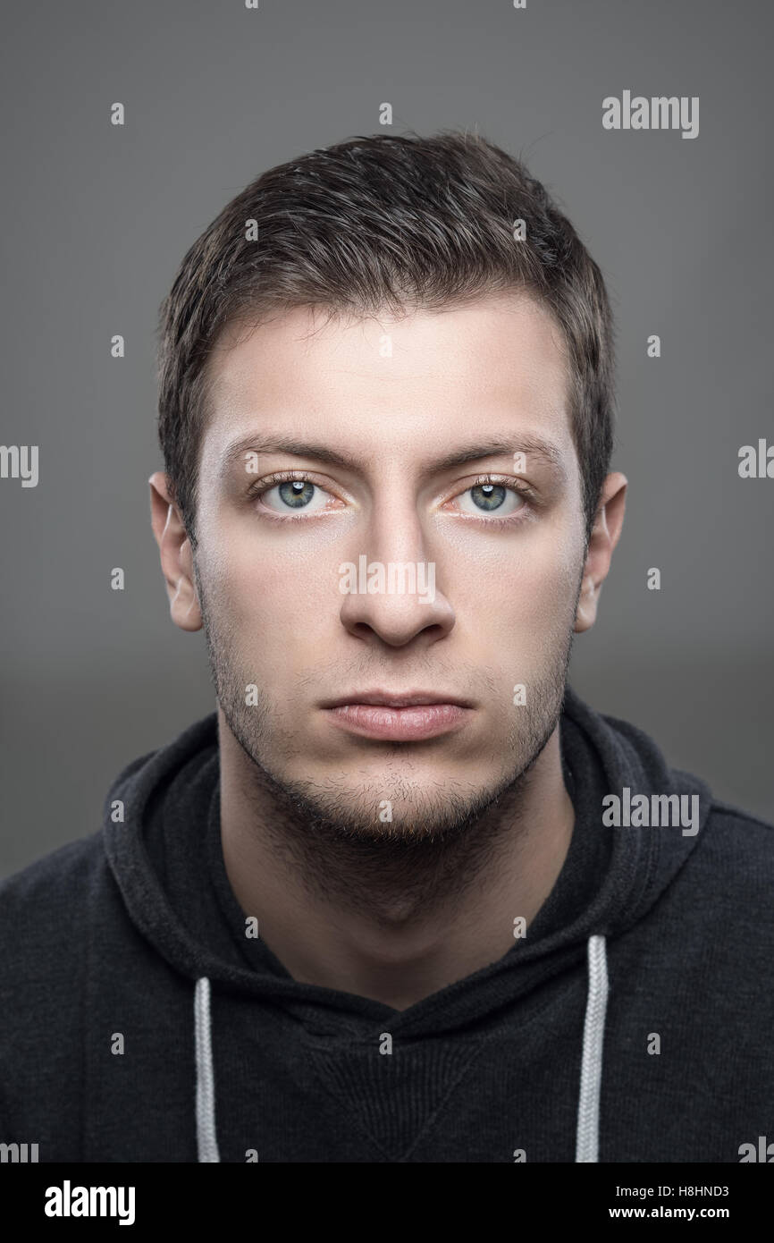 Close up portrait of young vertical moody casual man wearing sports hoodie looking at camera Banque D'Images