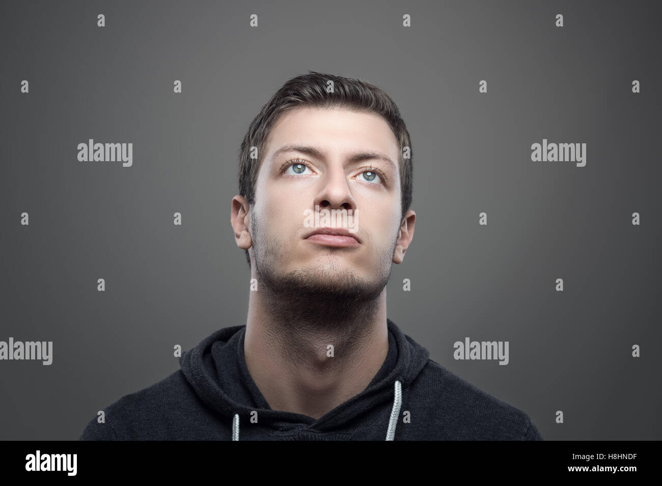 Moody portrait de jeune homme à la recherche jusqu'à l'allume visage sur fond gris Banque D'Images