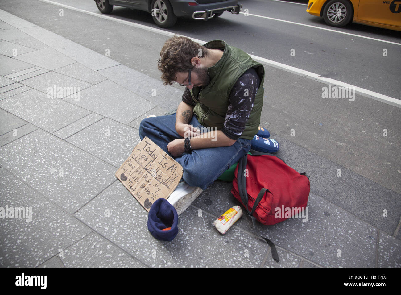 Sans-abri assis sur le trottoir, demander de l'aide le long de la 7e Avenue à Manhattan. Banque D'Images