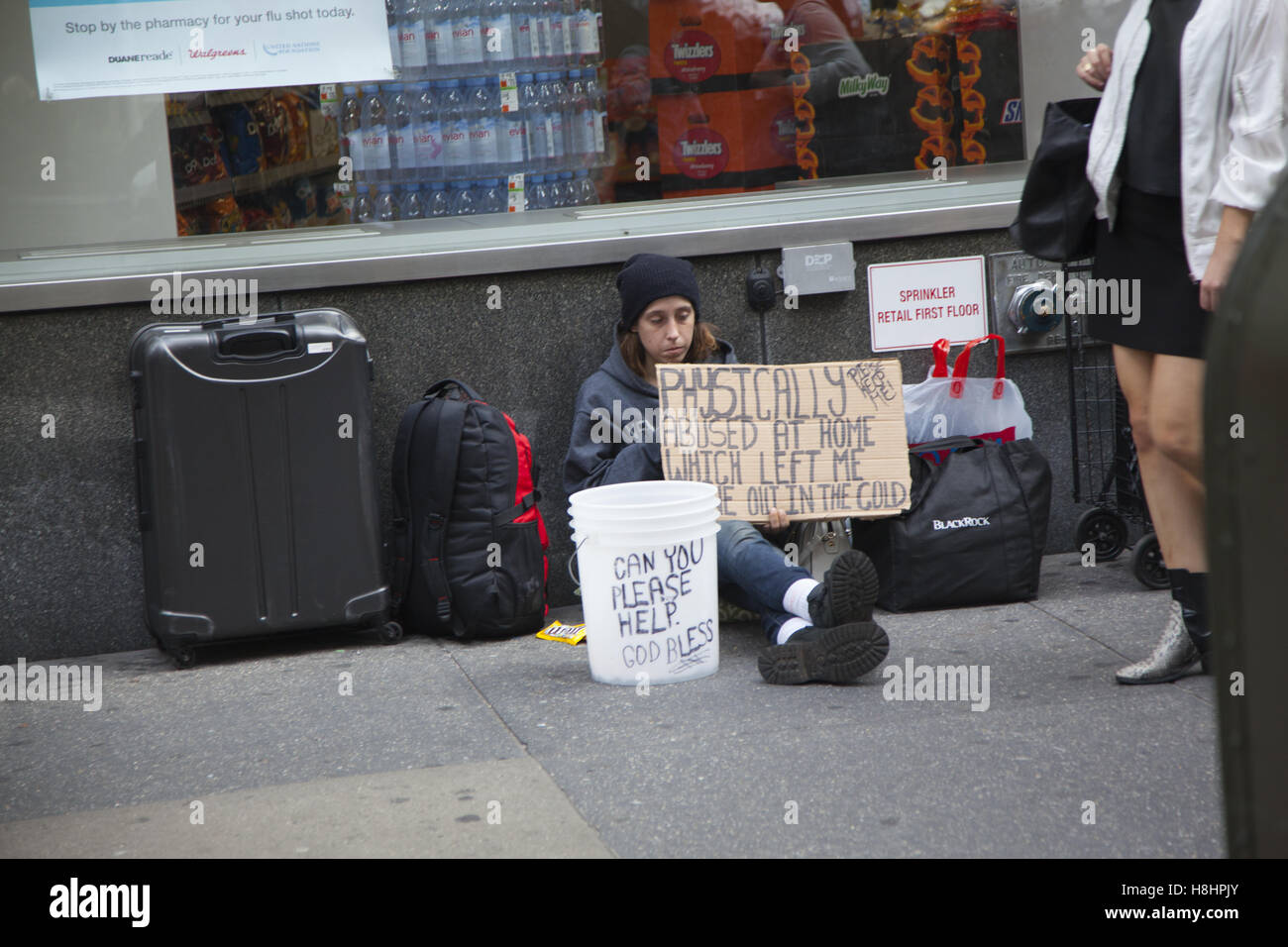 Sans-abri assis sur le trottoir, demander de l'aide le long de la 7e Avenue à Manhattan. Banque D'Images