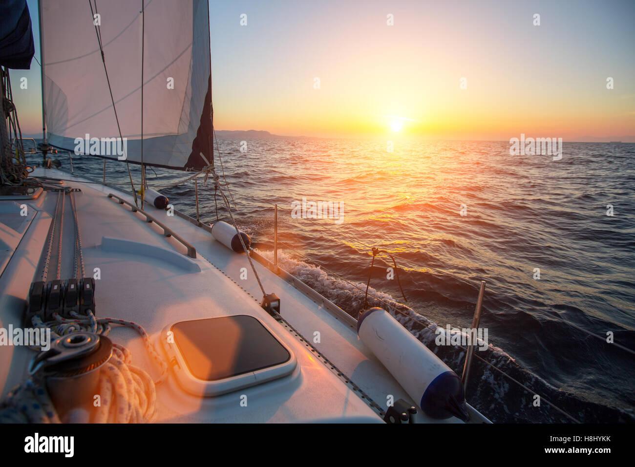 Incroyable coucher du soleil en mer prise d'un yacht luxueux bateau. La Voile dans le vent à travers les vagues. Banque D'Images