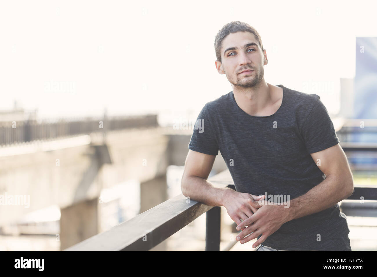 Les hommes dans le noir T-shirt appuyé contre la rambarde dans l'espace urbain. La beauté des hommes. Mode de rue. Banque D'Images