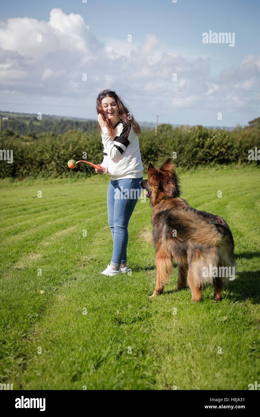 Jeune femme jette une boule pour son chien un berger allemand. Banque D'Images